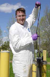[Photo of scientist holding radar cable leading into borehole]