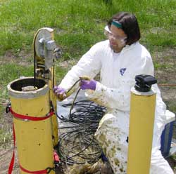 [Photo of scientist pulling radar cable, with oil splased onto protective clothing]