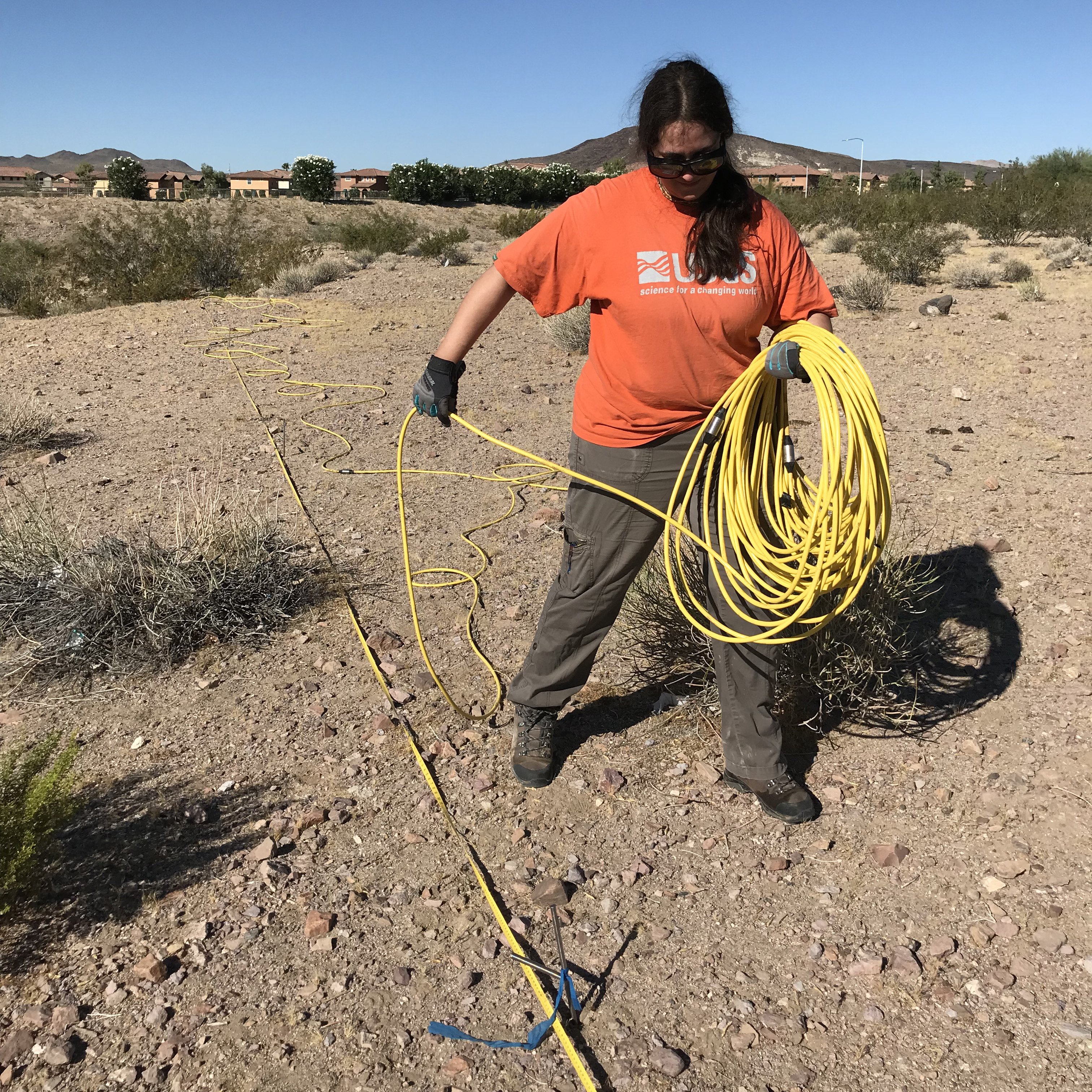  [ Photo of scientist deploying yellow cable in the field ]