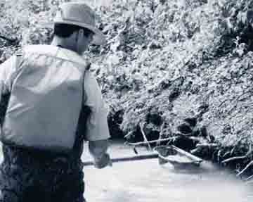 Photo of a technician collecting a water sample at a field site