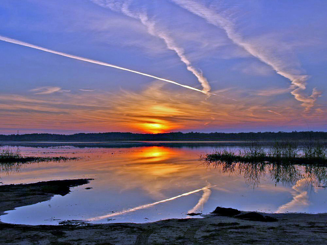 Photo of a condensation trails made by a high-flying airplanes, over Lake Jackson, Florida. Credit: Betsy Kellenberger.