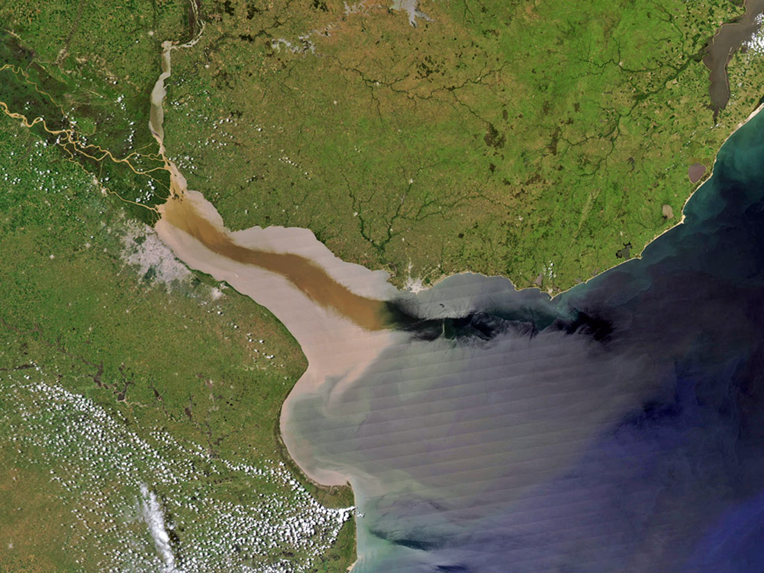 Satellite view of La Plata River discharge to the Atlantic Ocean. One way minerals and salts are deposited into the oceans is from outflow from rivers, which drain the landscape, thus causing the oceans to be salty.