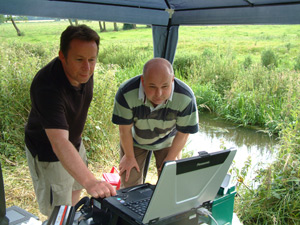  [Photo: scientists operate laptop at field site.] 